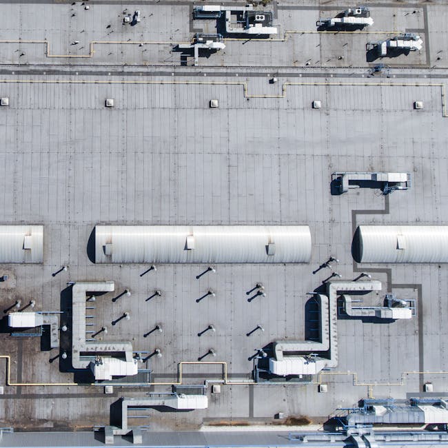 Aerial top view of a factory roof showcasing industrial pipes and structures.